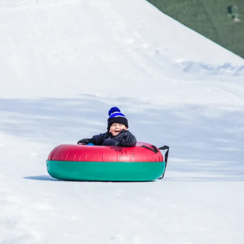 a person riding a snowboard down a snow covered slope